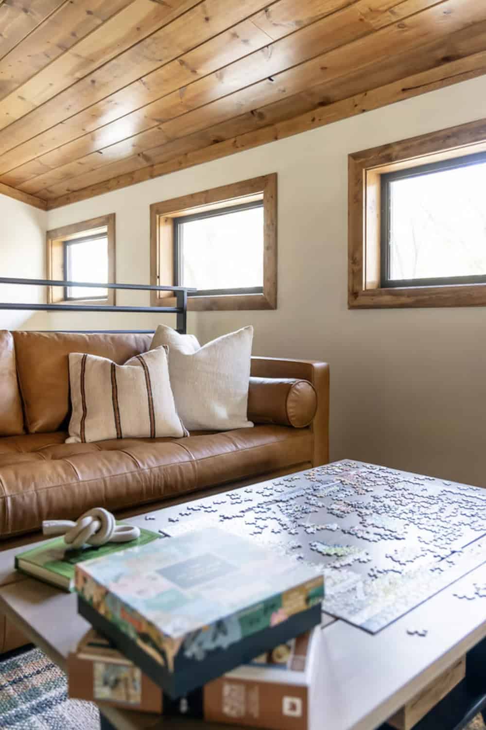 Loft seating area with tan leather sofa, linen pillows, and in-progress jigsaw puzzle on coffee table
