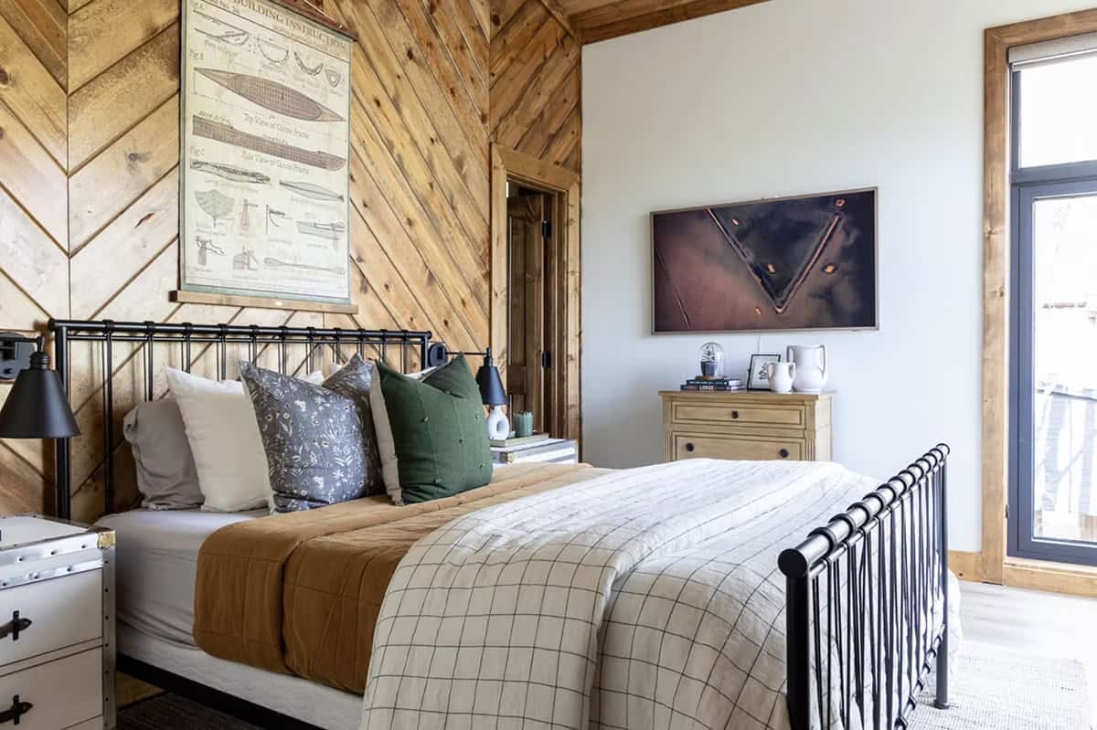 Bedroom with chevron wood accent wall, iron bed, green and floral pillows, canoe blueprint print, and Frame TV