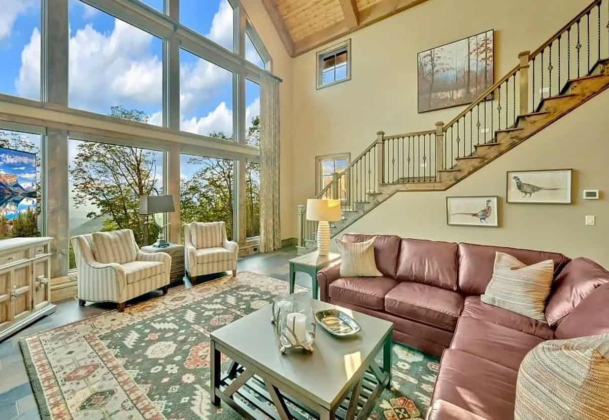 Bright living room with vaulted wood ceiling, leather sofa, and staircase with iron balusters