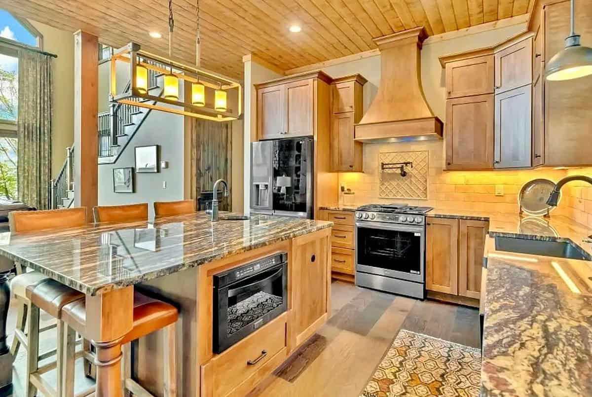 Kitchen with warm wood cabinets, custom range hood, and granite island with bar seating