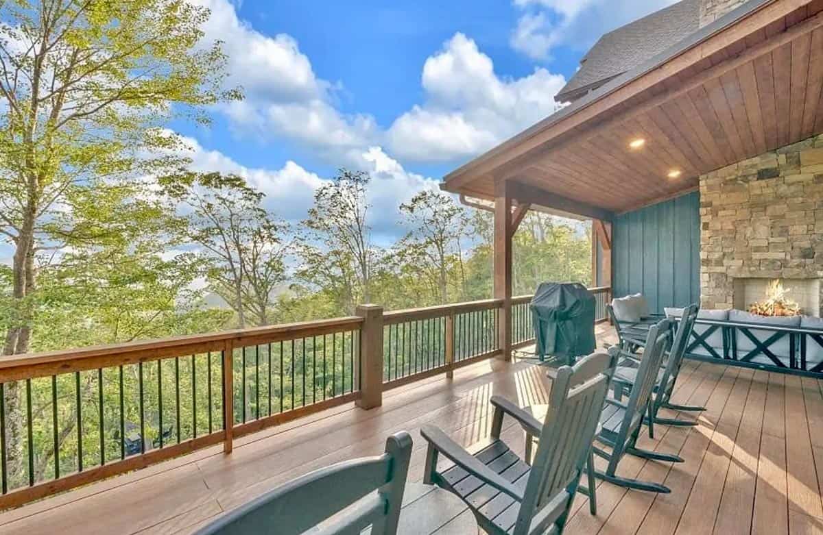 Expansive upper deck with mountain and treetop views and rocking chairs