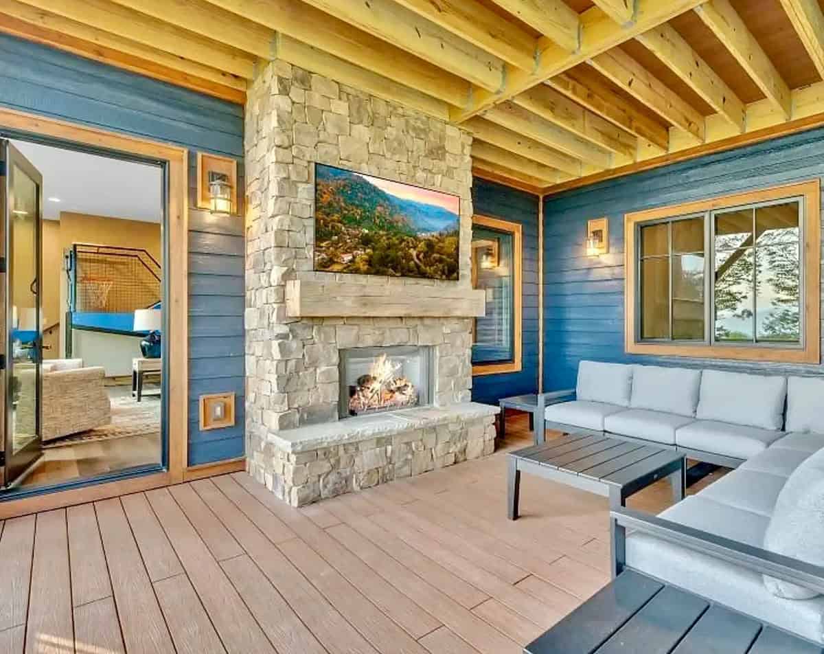 Covered outdoor living area with stone fireplace and white sectional sofa