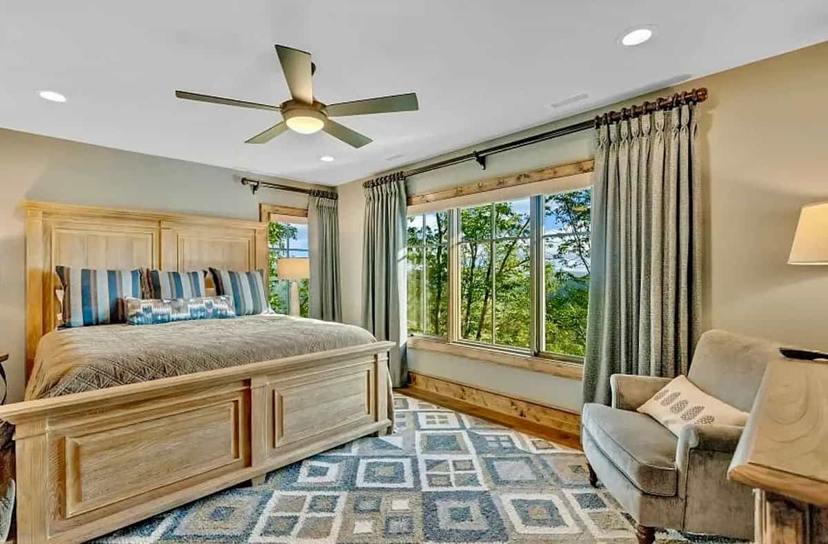 guest bedroom with a ceiling fan and drapery