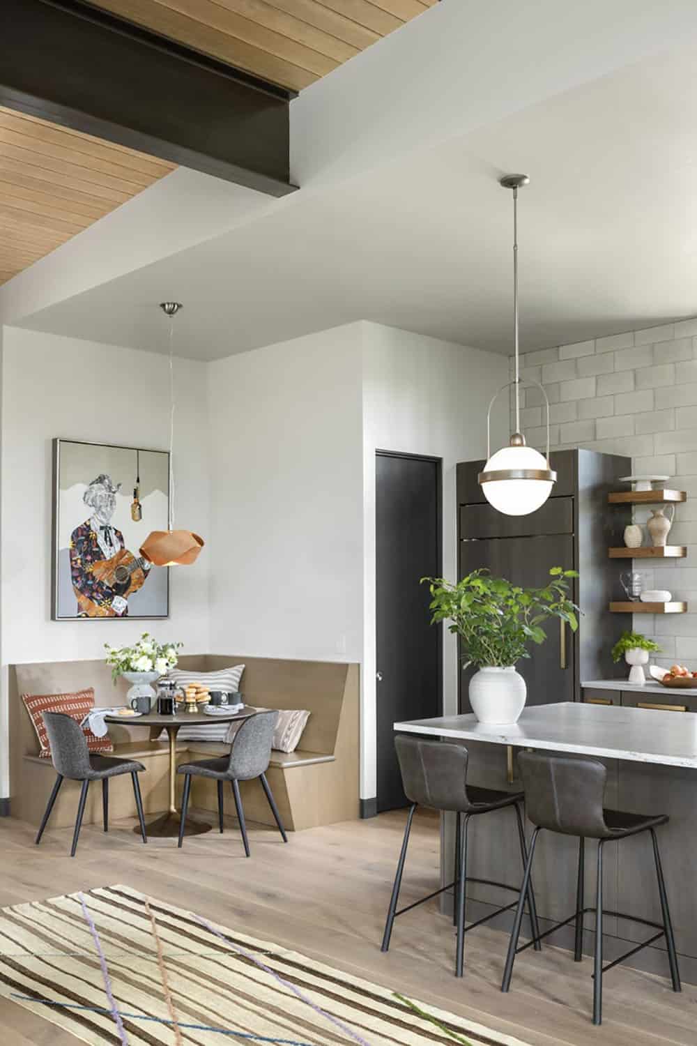 Kitchen banquette nook with copper pendant light beside island with globe pendants