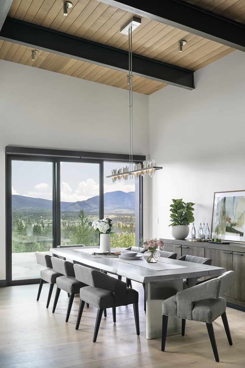 Dining room with concrete table, gray upholstered chairs, and mountain views