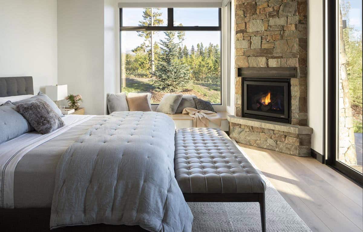 Primary bedroom with corner stone fireplace, window seat, and tufted bench