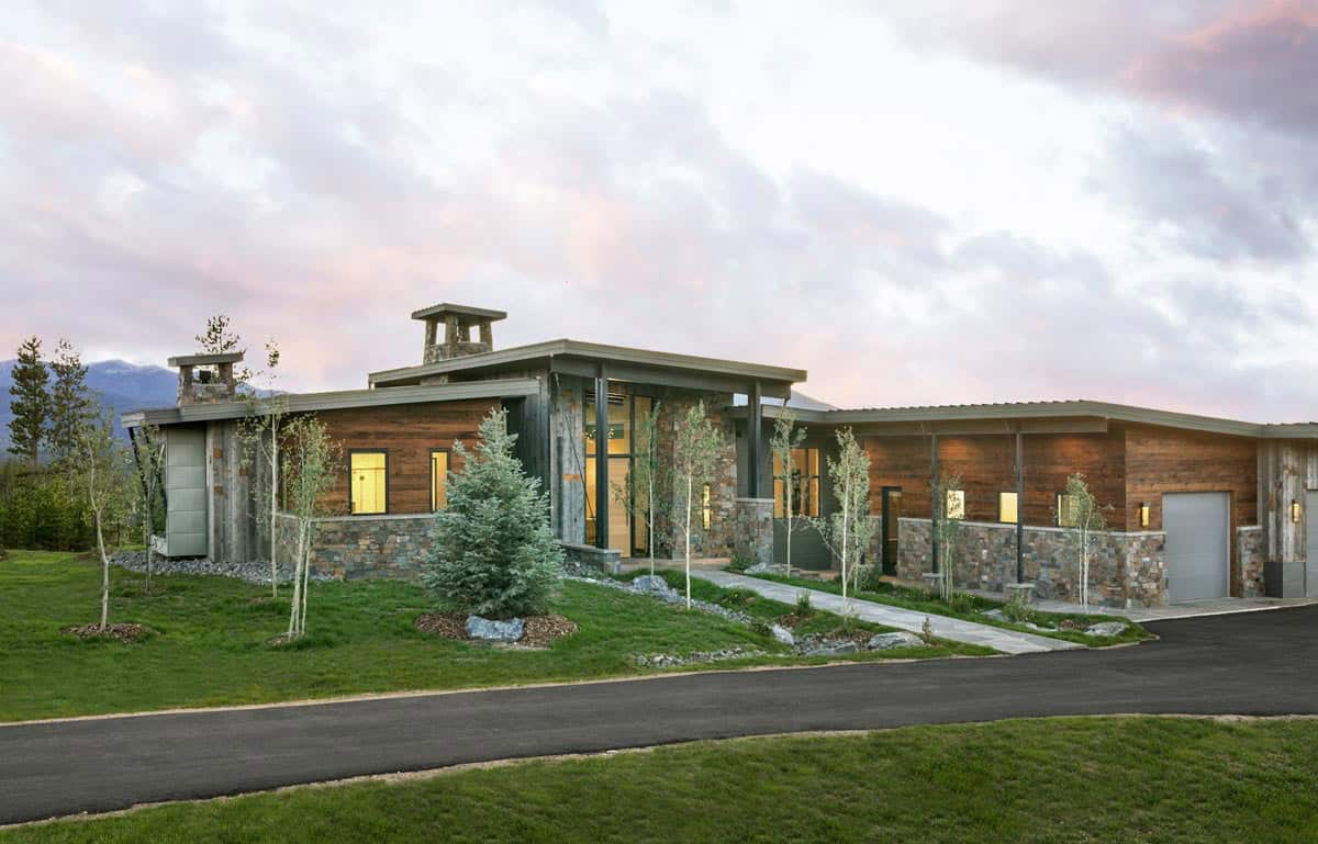 Full exterior view at dusk showing reclaimed wood, stone facade, and flat roofline