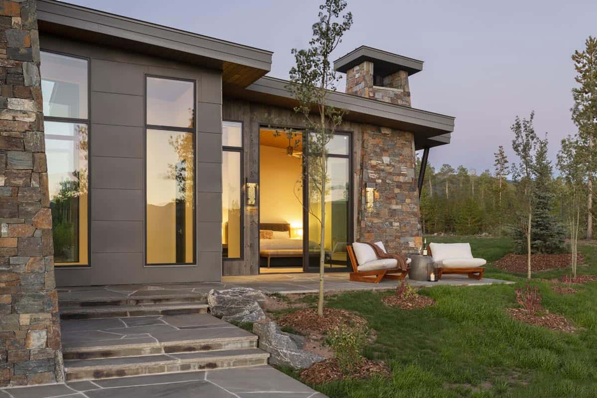 Primary suite exterior patio at dusk with teak lounge chairs and sliding glass doors