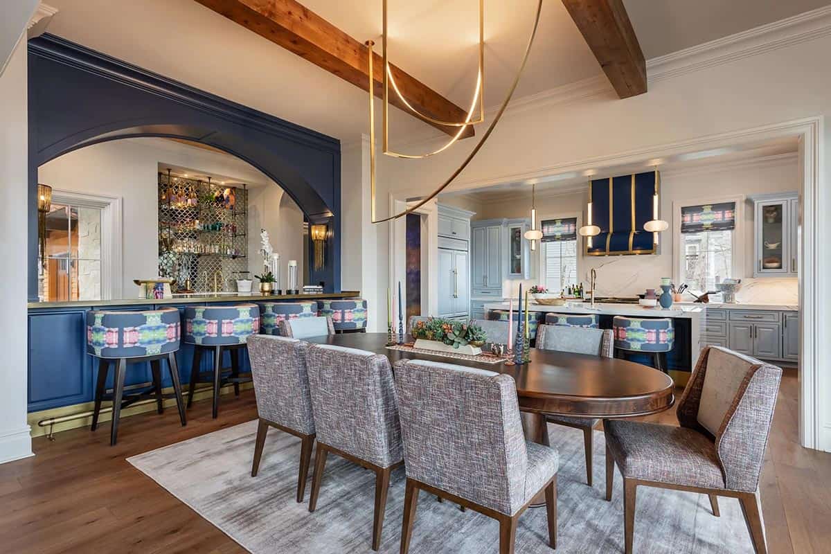 Open dining area with navy bar nook, gold chandelier, and blue kitchen beyond