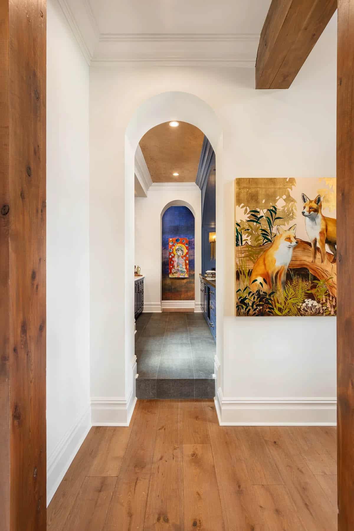 White hallway with arched doorways, fox artwork, and view into navy bar