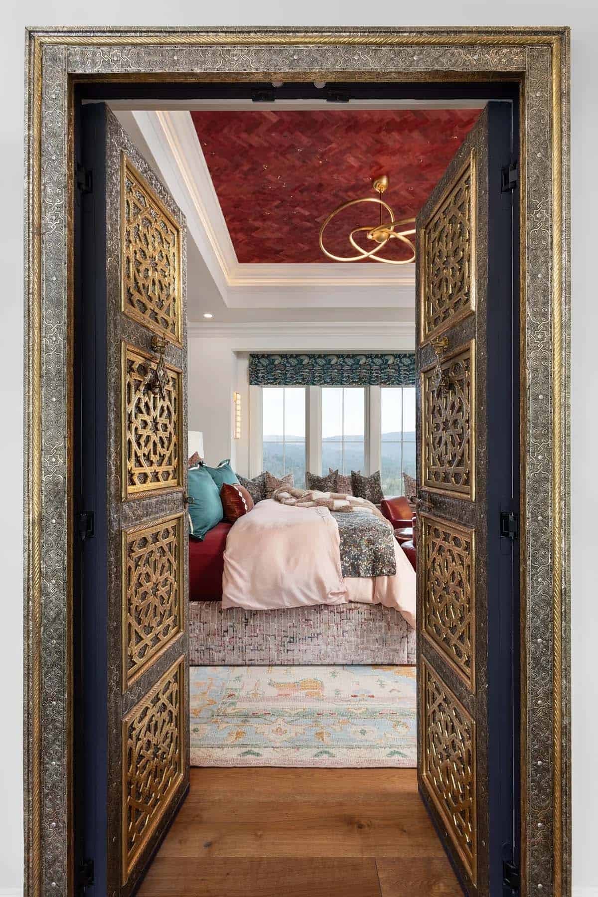 Ornate Moroccan-style doors opening into bedroom with red herringbone ceiling