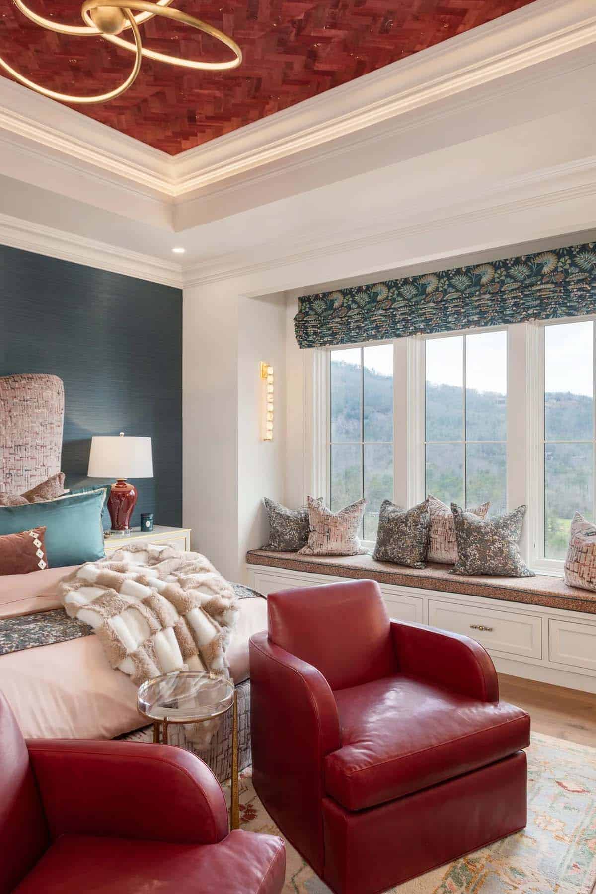 Primary bedroom with red leather chairs, tufted window seat, mountain views, and red ceiling
