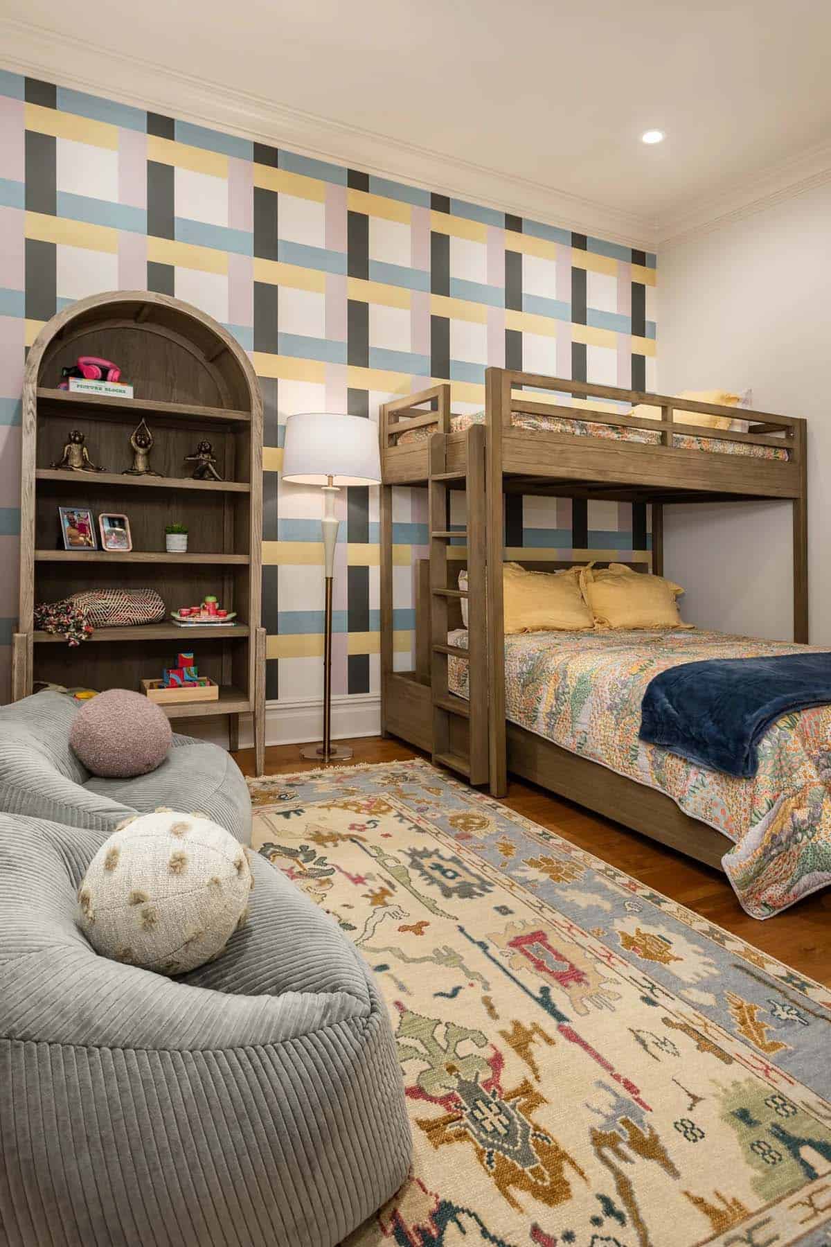 Kids' room with colorful plaid wallpaper, wooden bunk beds, and arched bookshelf