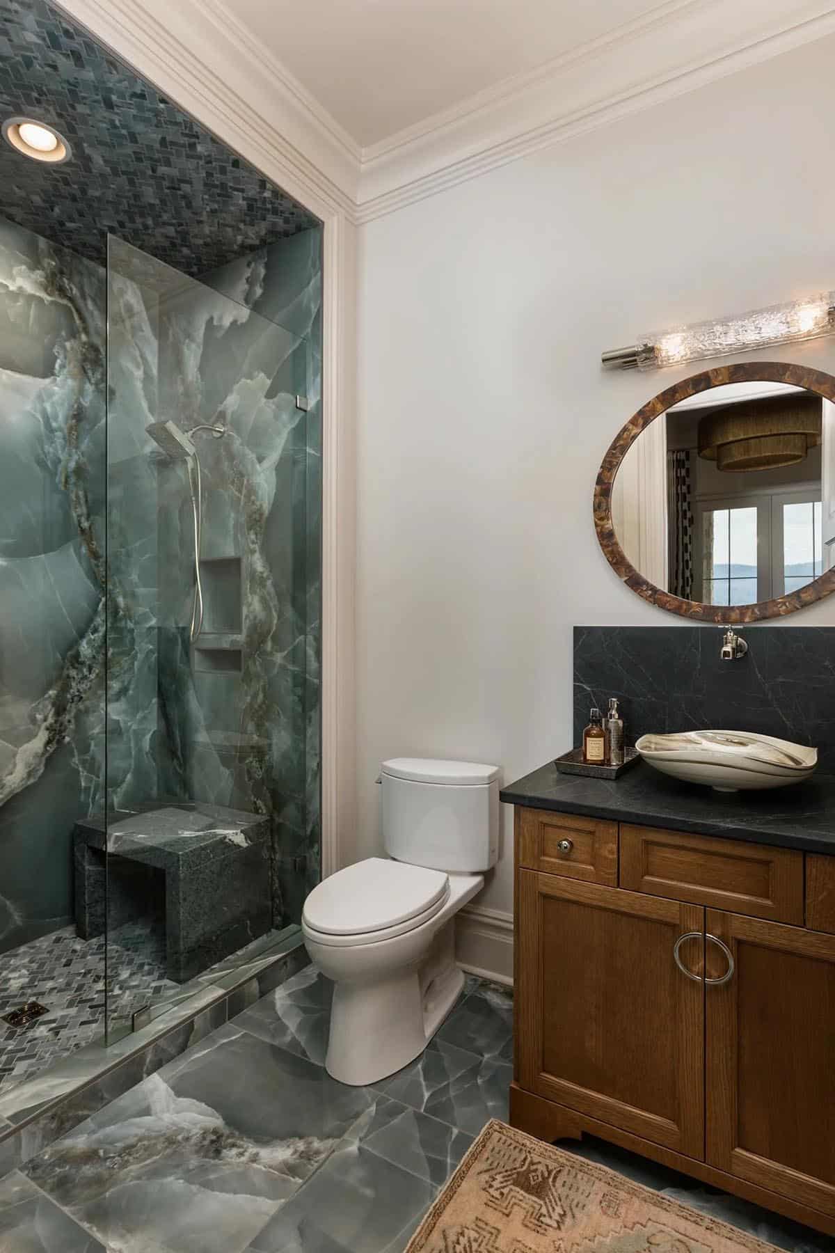 Guest bathroom with dramatic green onyx shower, wood vanity, and black stone countertop