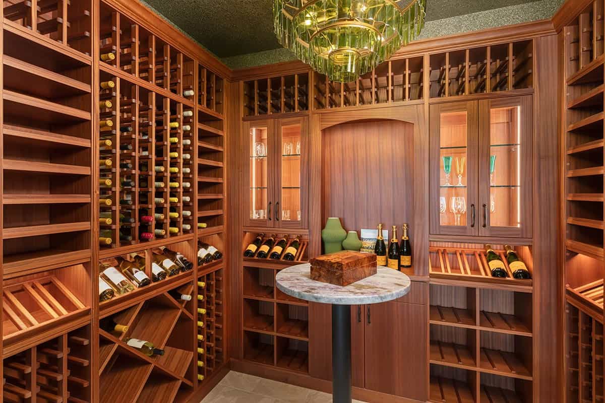 Custom cedar wine cellar with floor-to-ceiling racks, marble bistro table, and green glass chandelier
