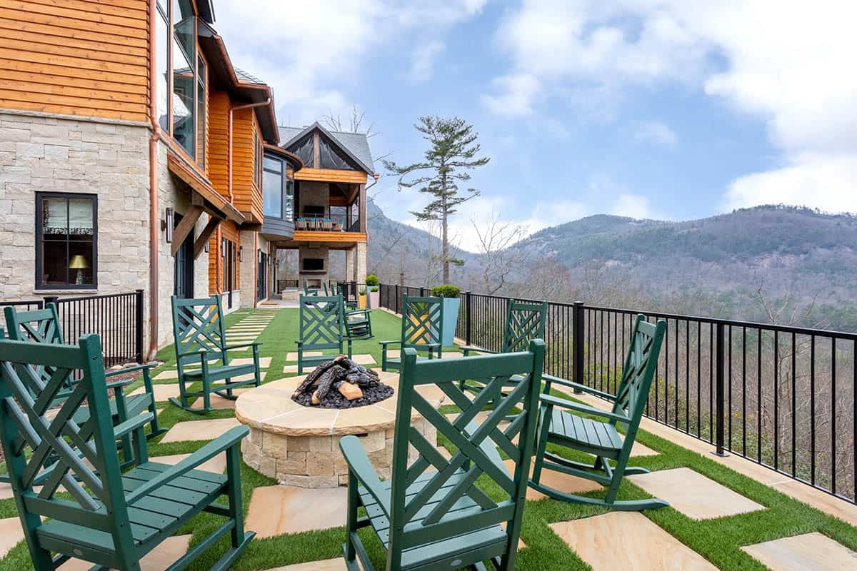 Outdoor patio with green rocking chairs around stone fire pit and North Carolina mountain views