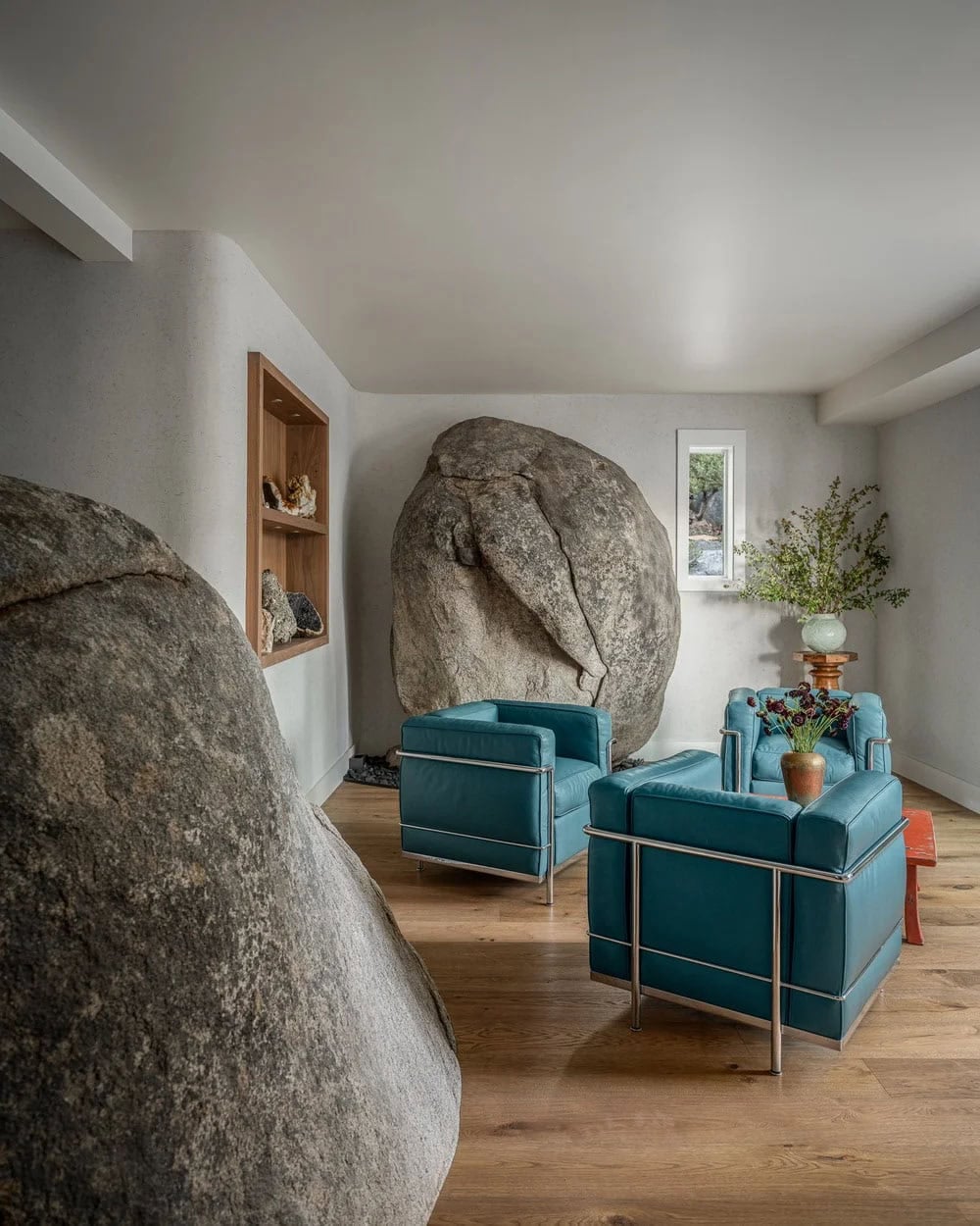 Sitting room with teal leather chairs and massive granite boulders incorporated into interior