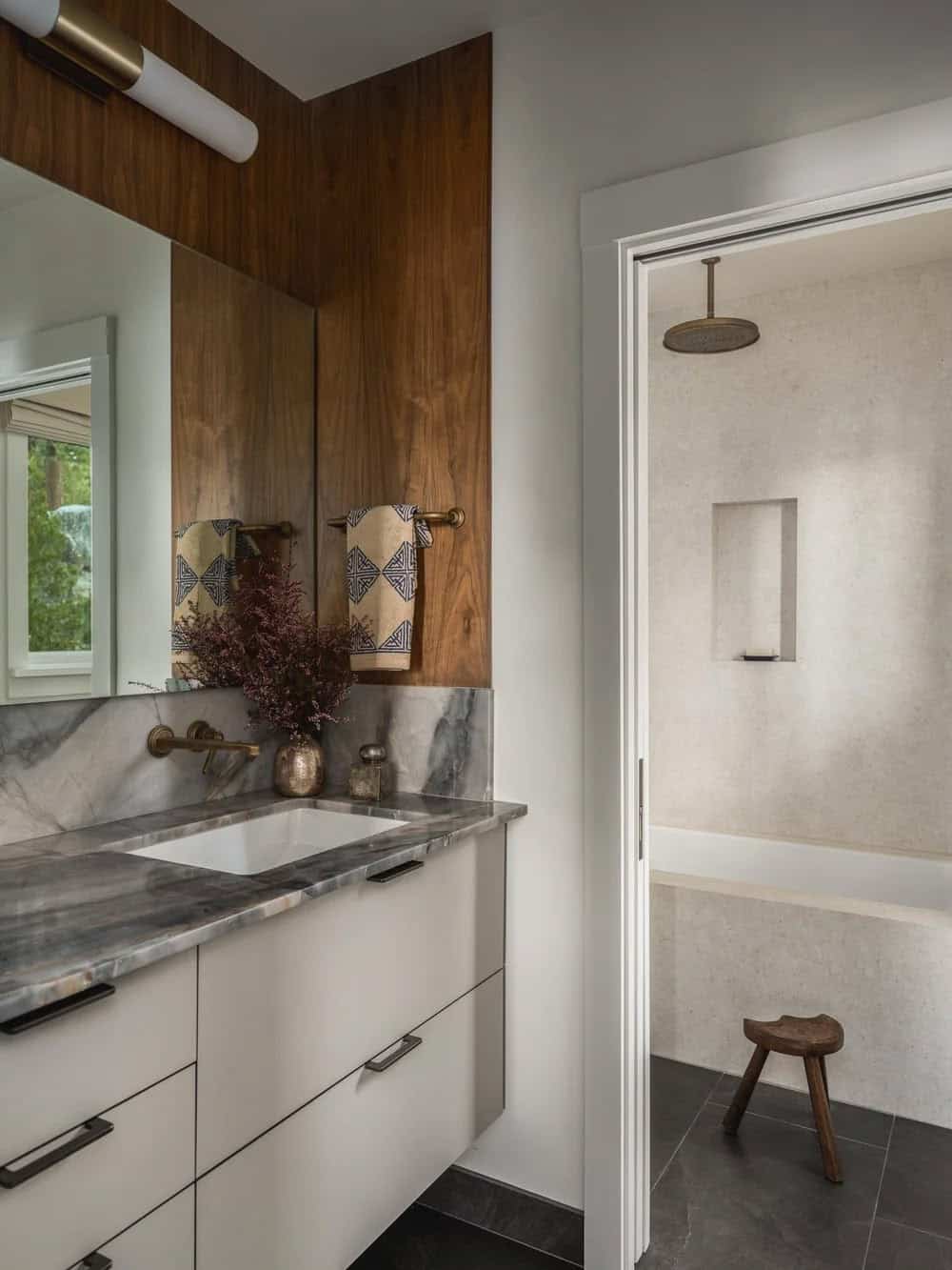 Bathroom vanity with marble countertop, walnut paneling and walk-in rain shower