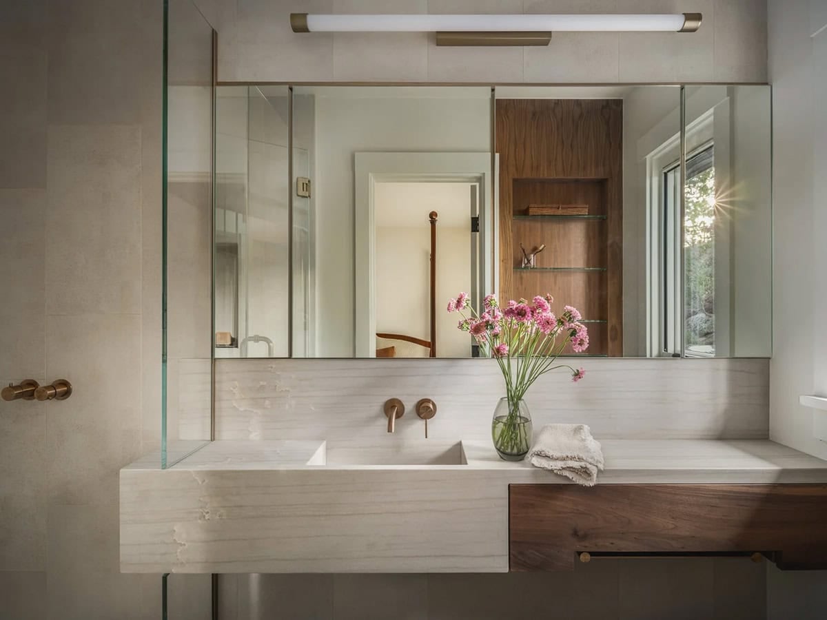 Floating marble vanity with wall-mount bronze faucets and full-width mirror cabinet