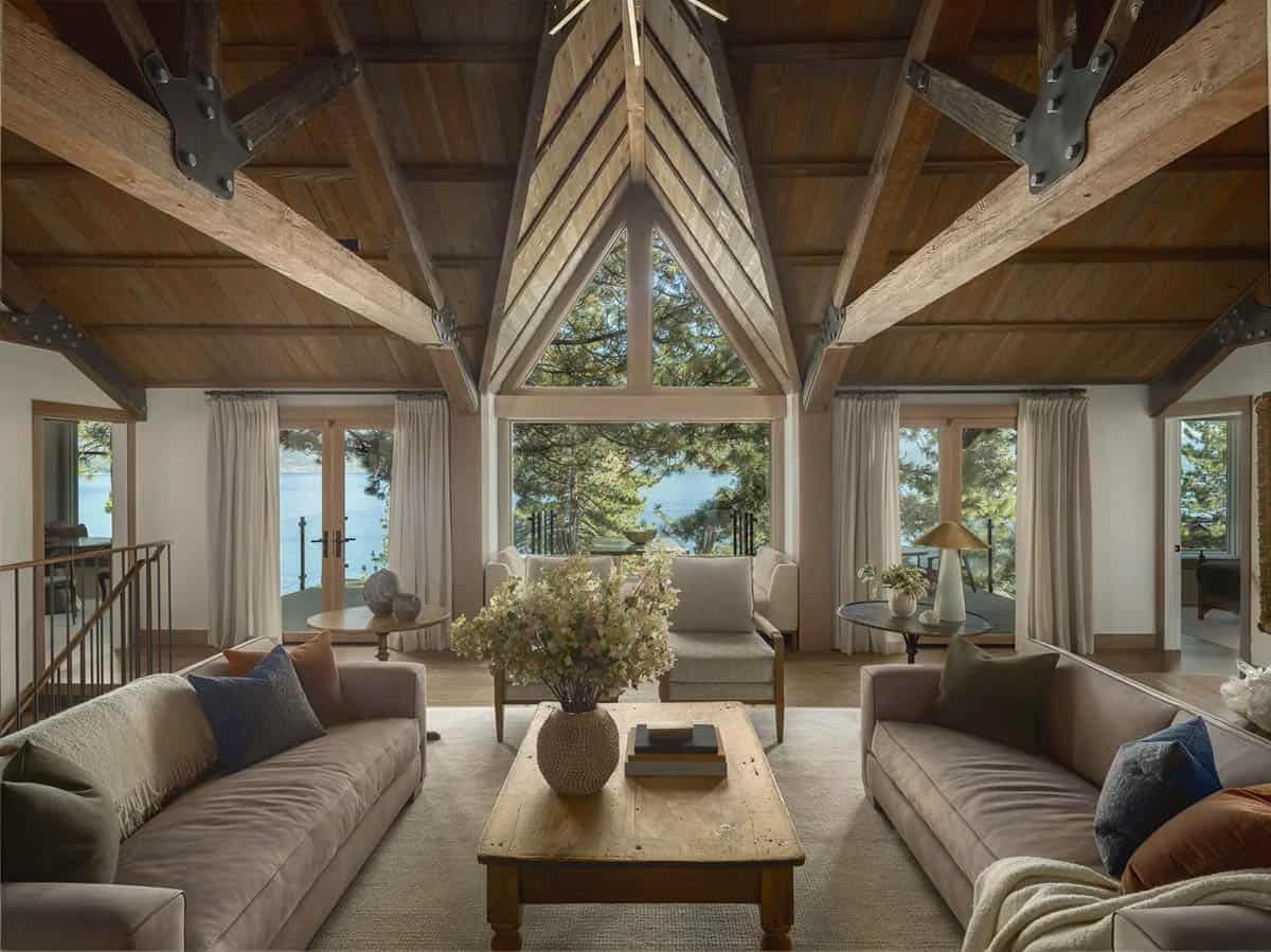 Living room with soaring timber trusses, lake views through triangular gable window