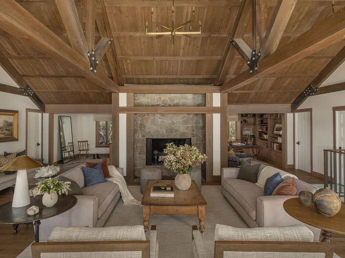 Great room with stone fireplace, exposed timber trusses and built-in bookshelves