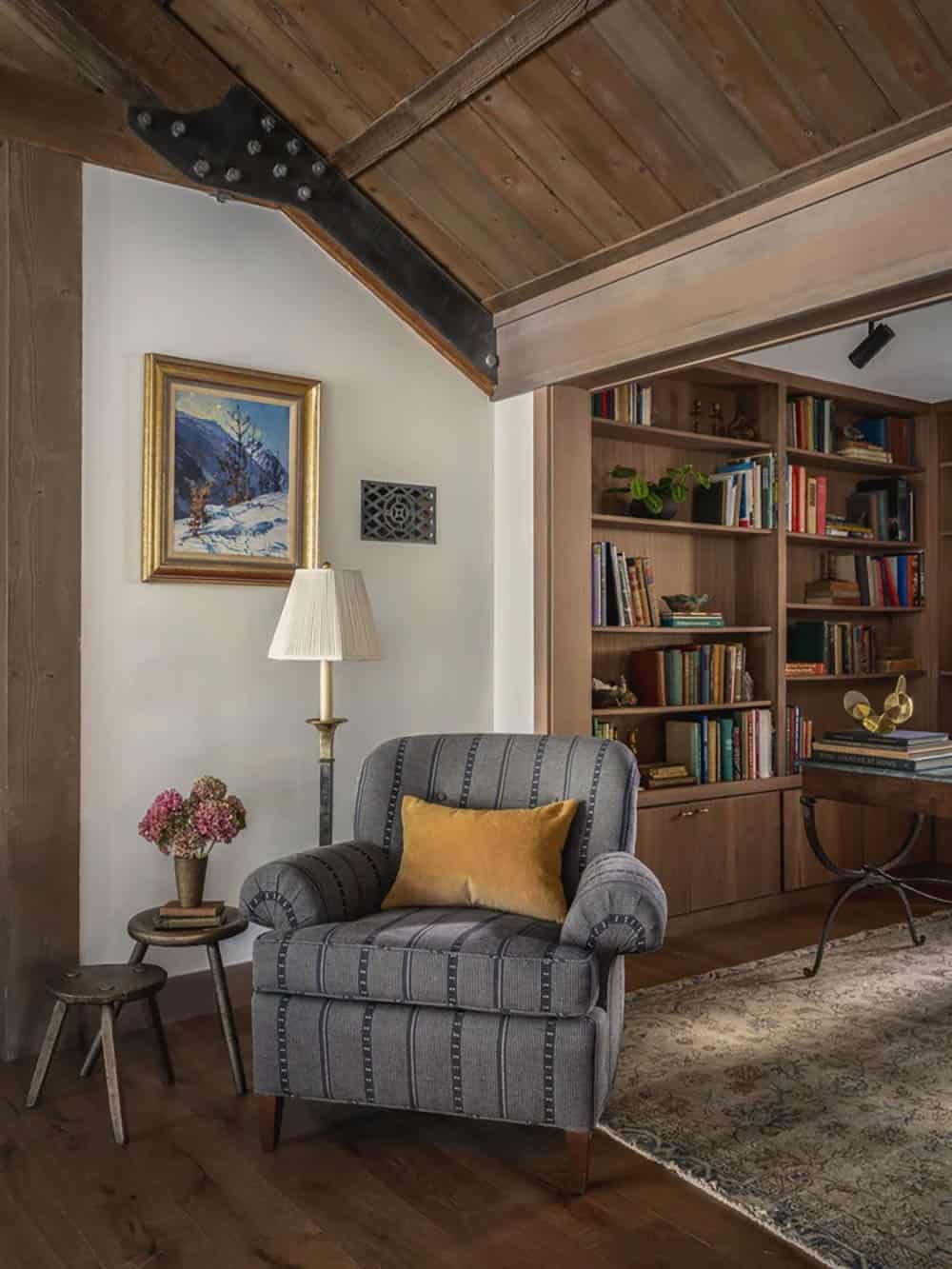 Reading nook with striped armchair, built-in bookshelves and mountain landscape painting