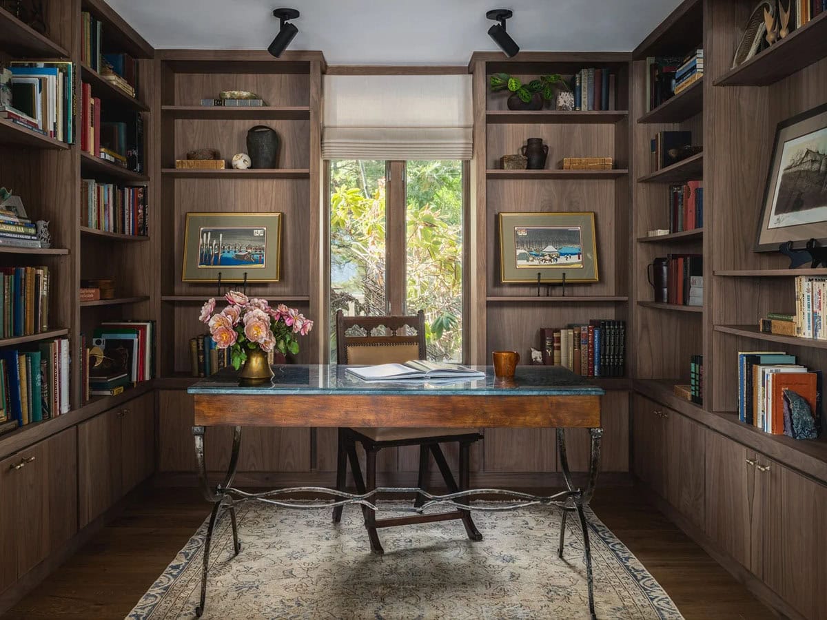 Wood-paneled home library with floor-to-ceiling bookshelves and antique writing desk