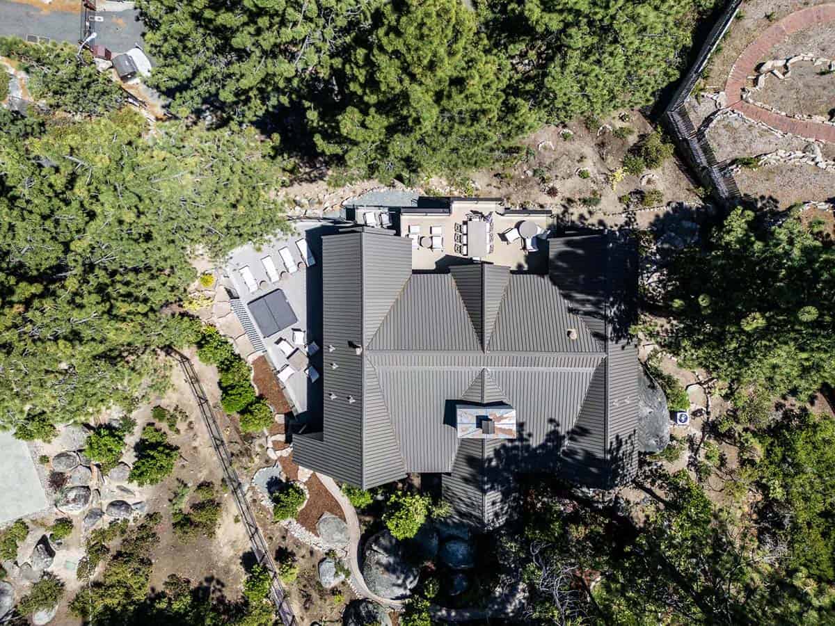 Overhead aerial view of mountain lodge metal roof nestled among pine trees