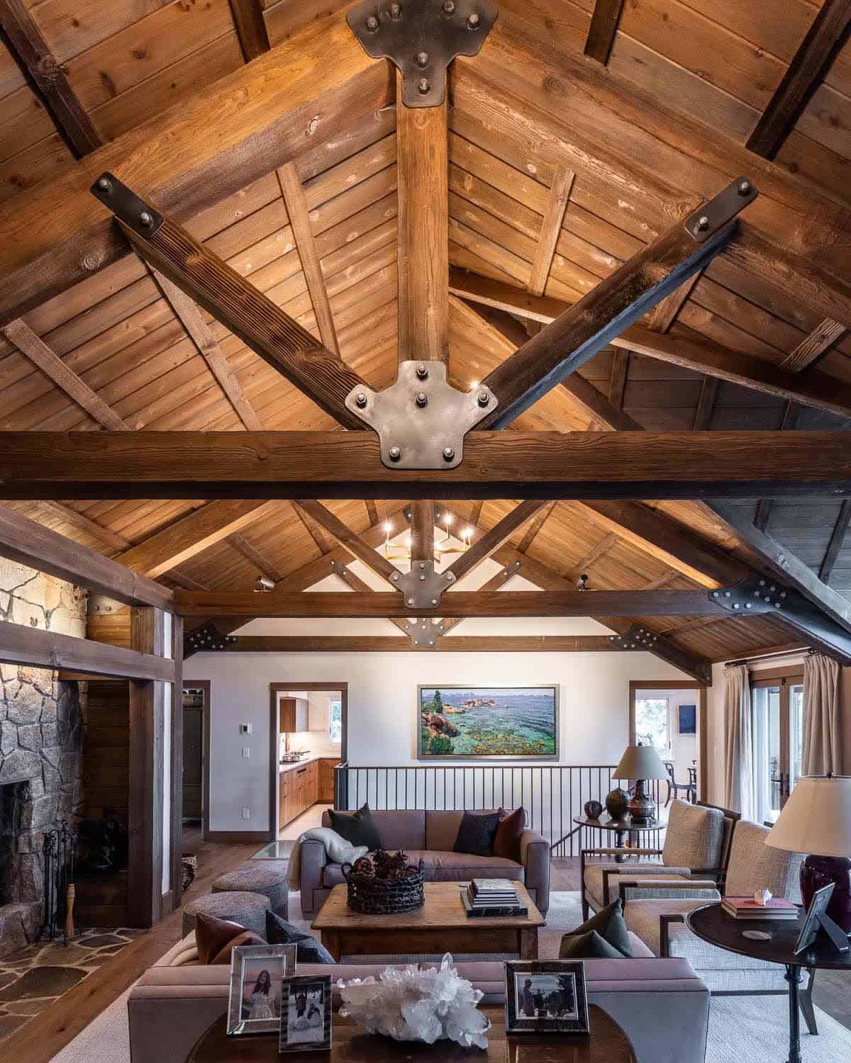 Looking up at dramatic exposed timber roof trusses with iron gusset plates in cathedral-ceiling lodge living room
