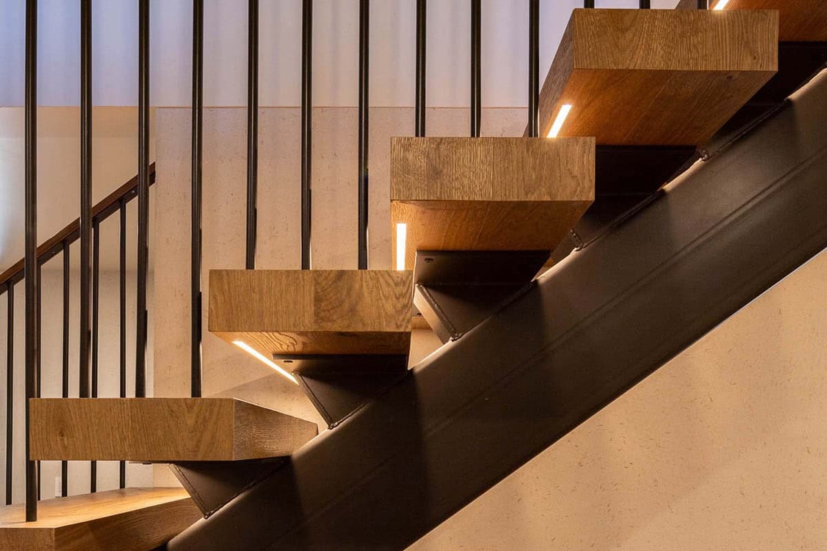 Close-up of cantilevered oak stair treads with integrated LED lighting and black steel mono-stringer construction