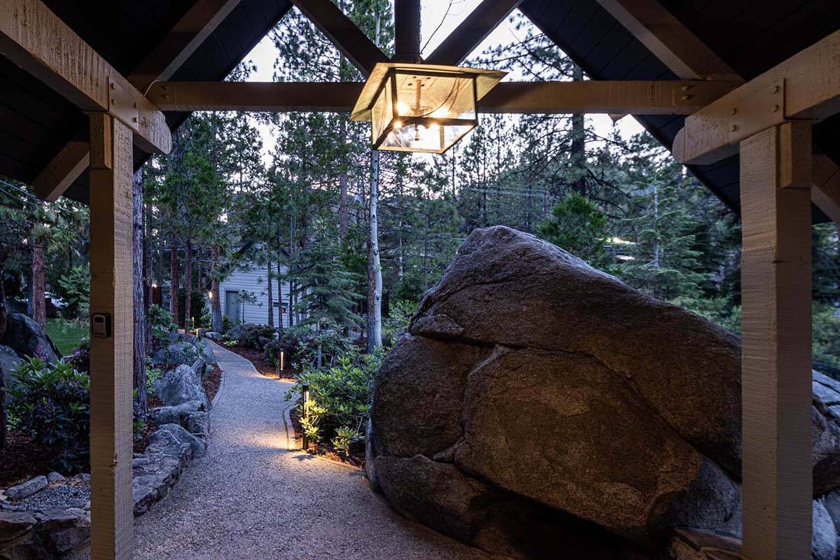 Mountain lodge exterior entry with a pathway and large boulder