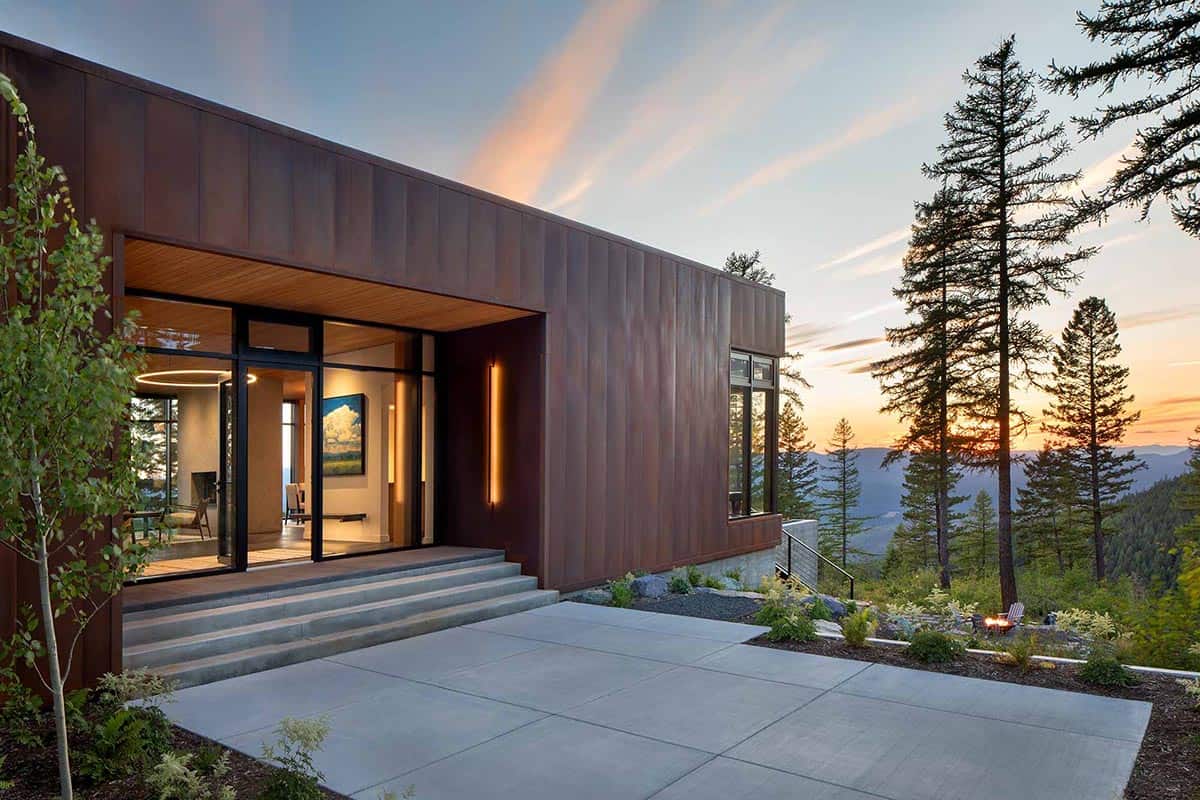 Corten steel entry facade with floor-to-ceiling glass doors and sunset mountain backdrop