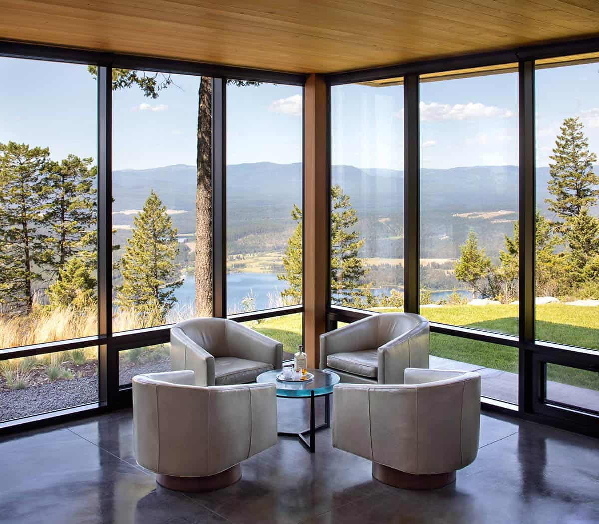 Four leather tub chairs arranged in glass corner room overlooking river valley and mountains