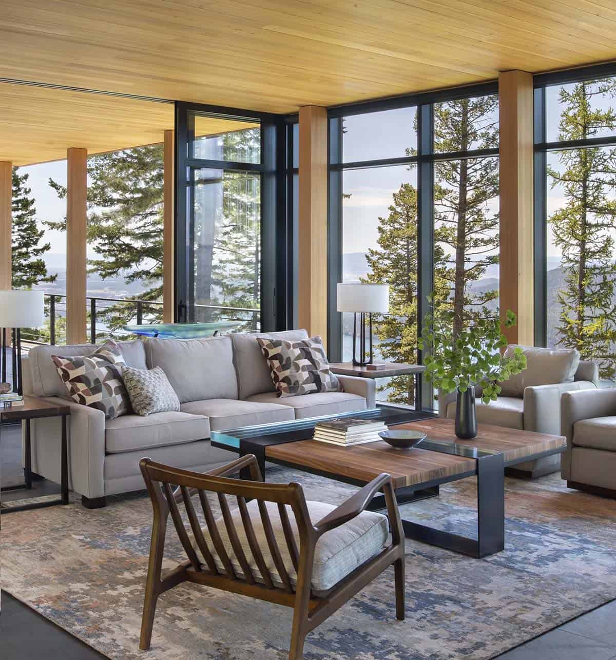 Living room seating group with walnut coffee table and lake views through black-framed glass walls