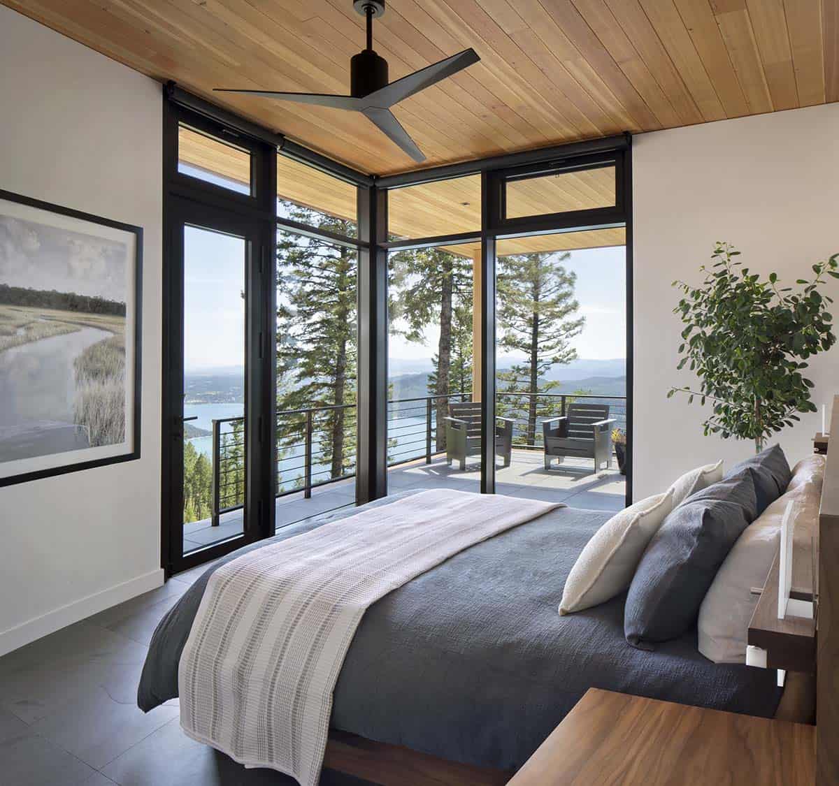 Primary bedroom with corner glass walls, cedar ceiling, and private balcony with lake views