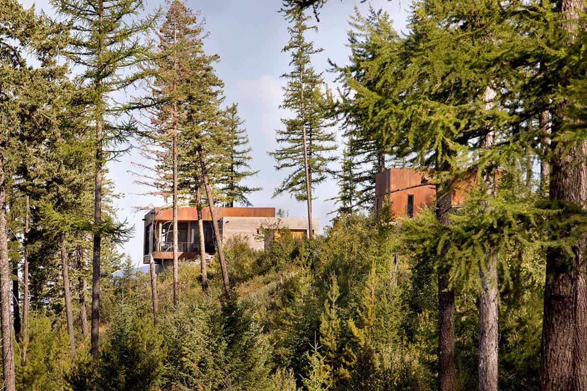 Mountain modern house glimpsed through dense pine forest on a Montana ridgeline