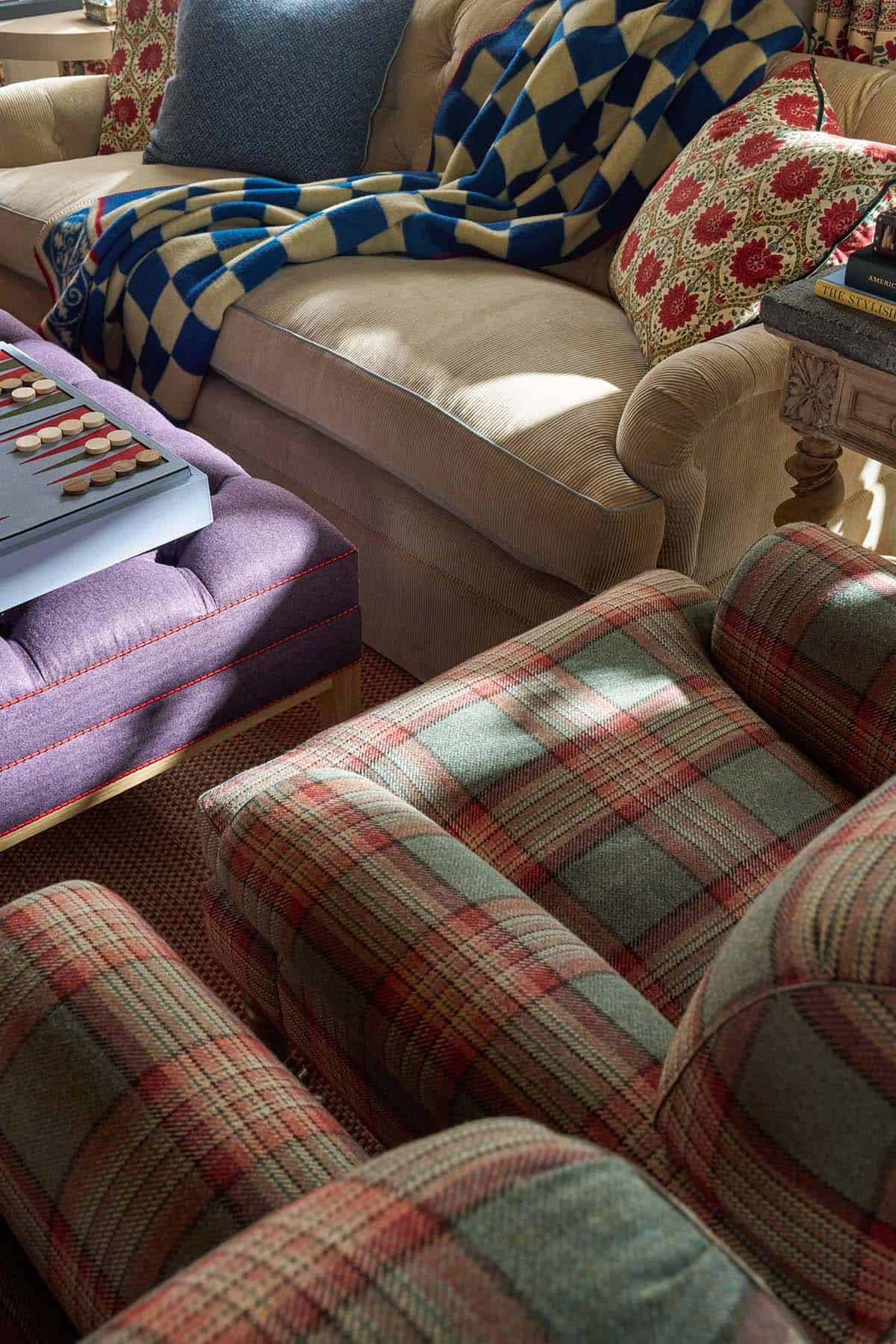 Close-up of plaid armchair, tufted purple ottoman, and checkered cashmere throw in family room