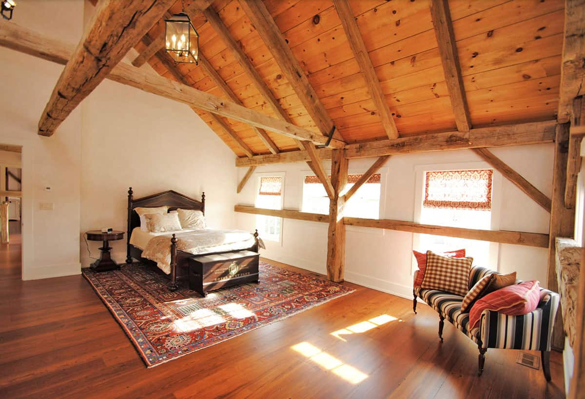 Bedroom with vaulted timber frame ceiling, dark wood four-poster bed, and Persian rug