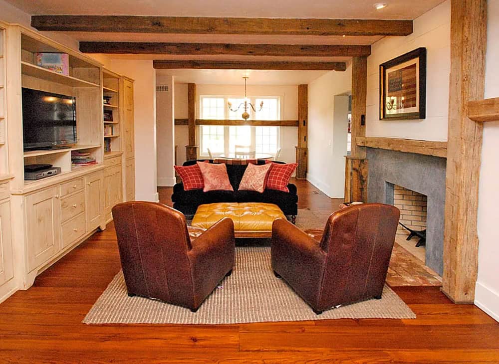 Family room with leather chairs, built-in media cabinet, stone fireplace, and exposed ceiling beams