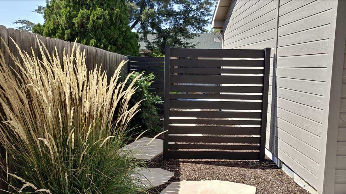 Narrow backyard pathway with flagstone flanked by privacy screens