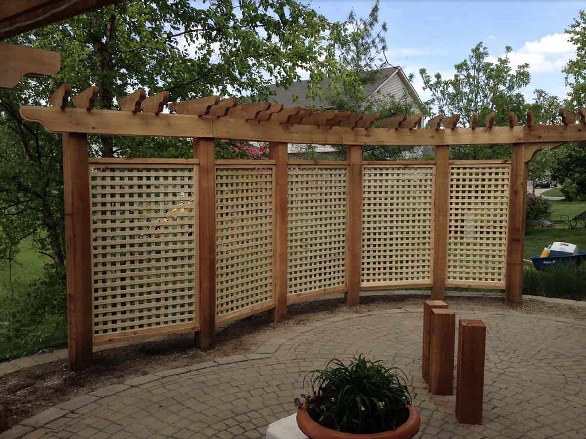 Curved pergola with lattice privacy screen panels on a stone patio