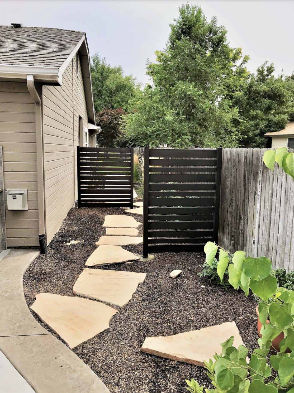 Narrow pathway with flagstone flanked by privacy screens