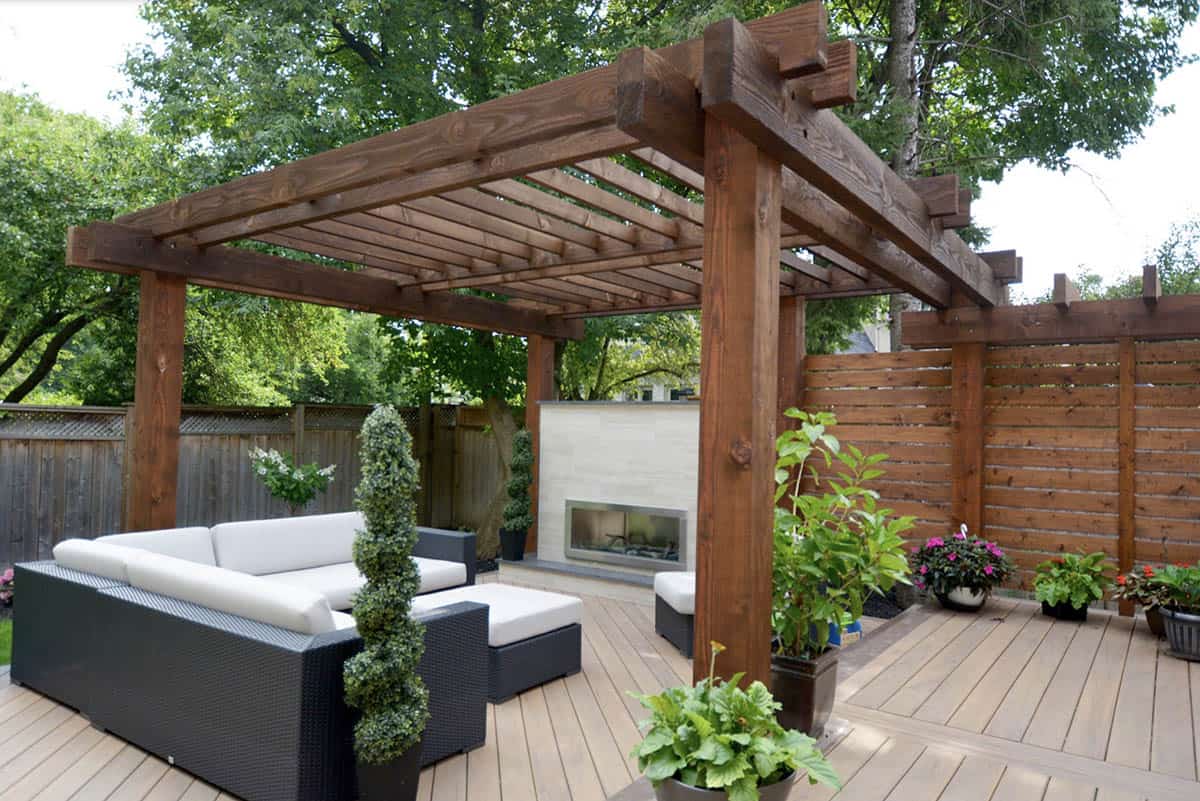 Modern wood pergola with horizontal slat privacy screen and outdoor fireplace on a deck