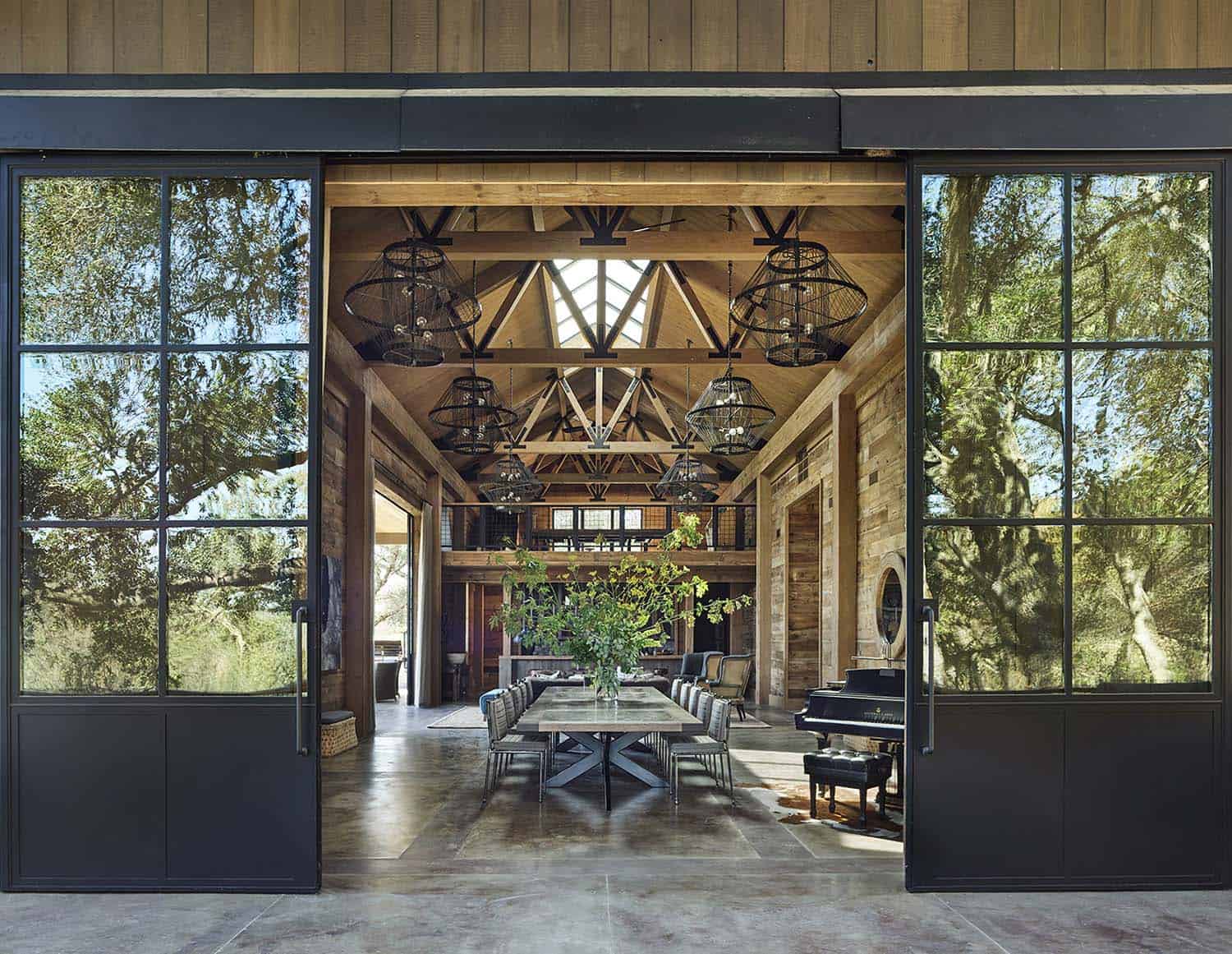 Rustic party barn interior with sliding steel doors, timber trusses and dining table