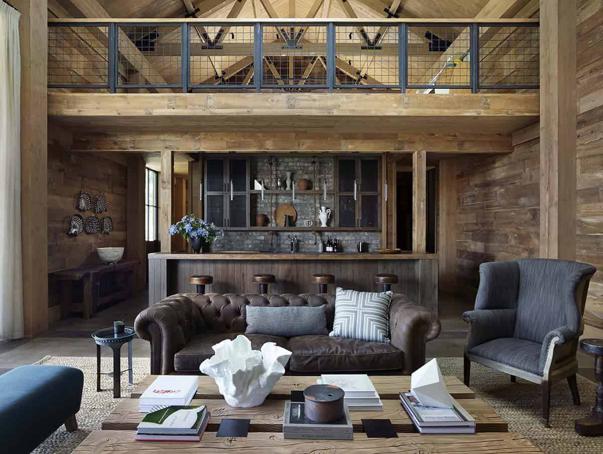 Living room with tufted leather sofas, mezzanine loft and rustic stone bar