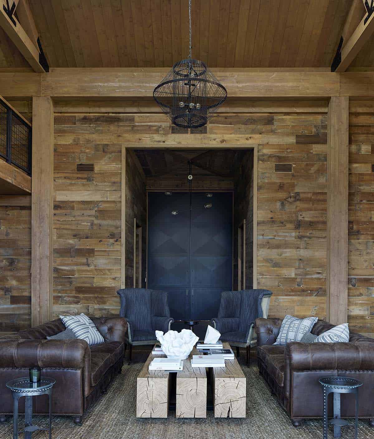 Barn living area with leather sofas, log coffee table and dramatic steel entry doors