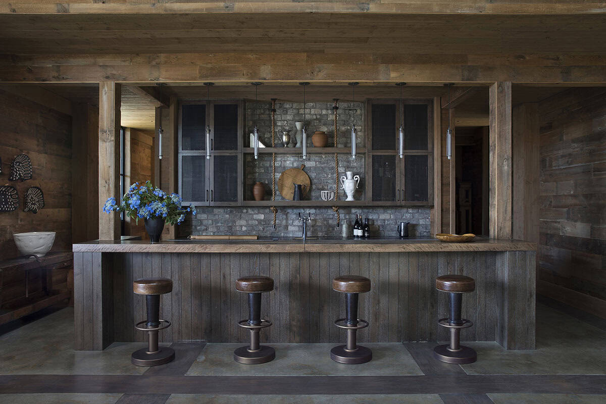 Rustic barn bar with reclaimed wood, brick backsplash, rope shelving and leather stools