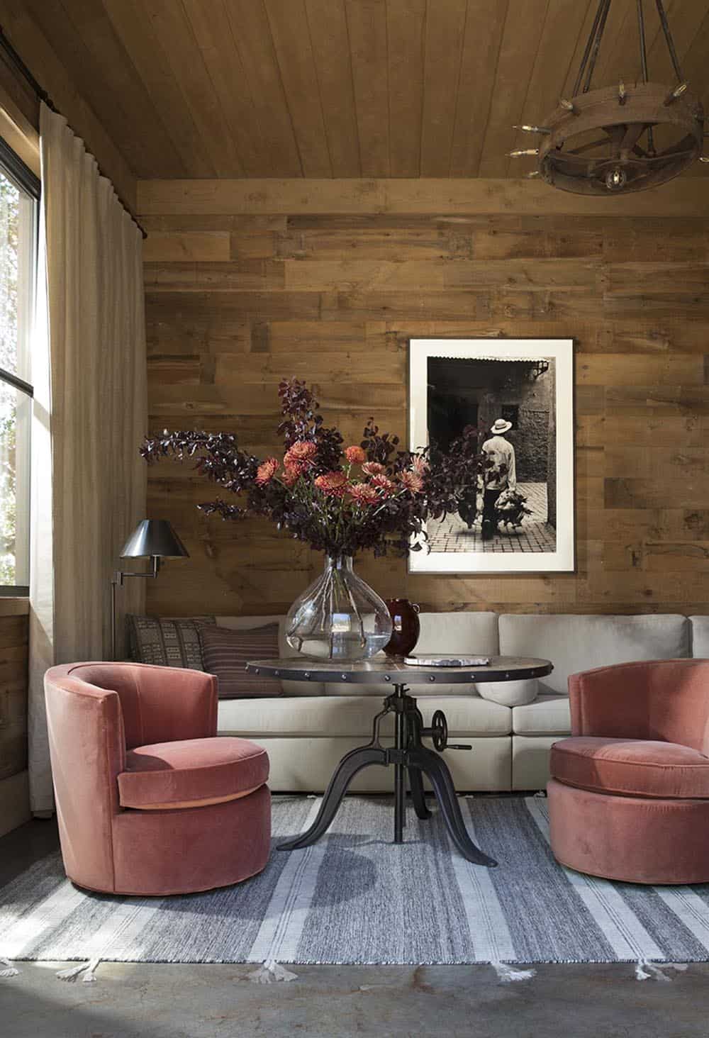 Sitting room with dusty rose velvet chairs, industrial crank table and black-and-white photography