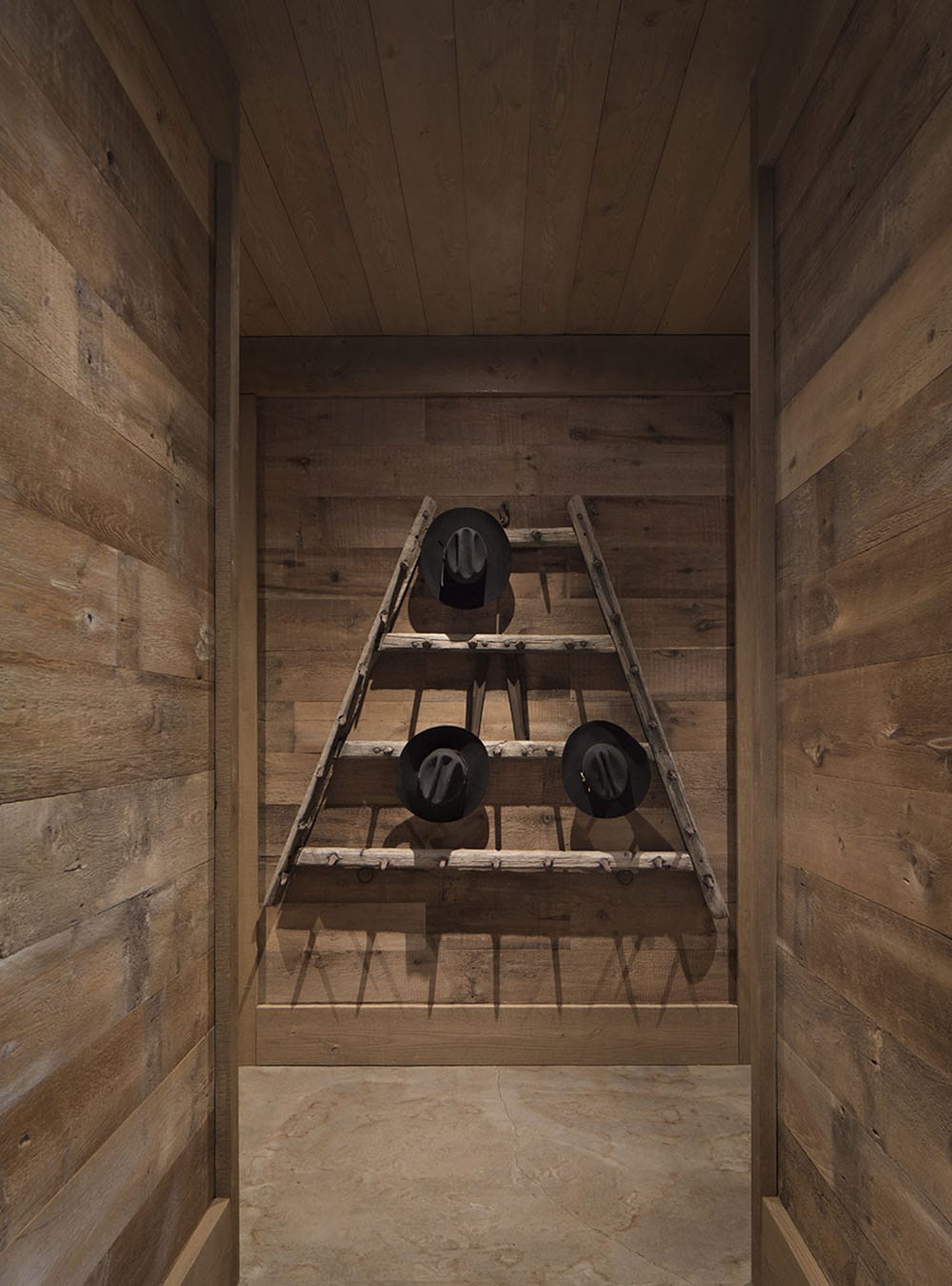 Rustic hallway with vintage wooden ladder displaying cowboy hats