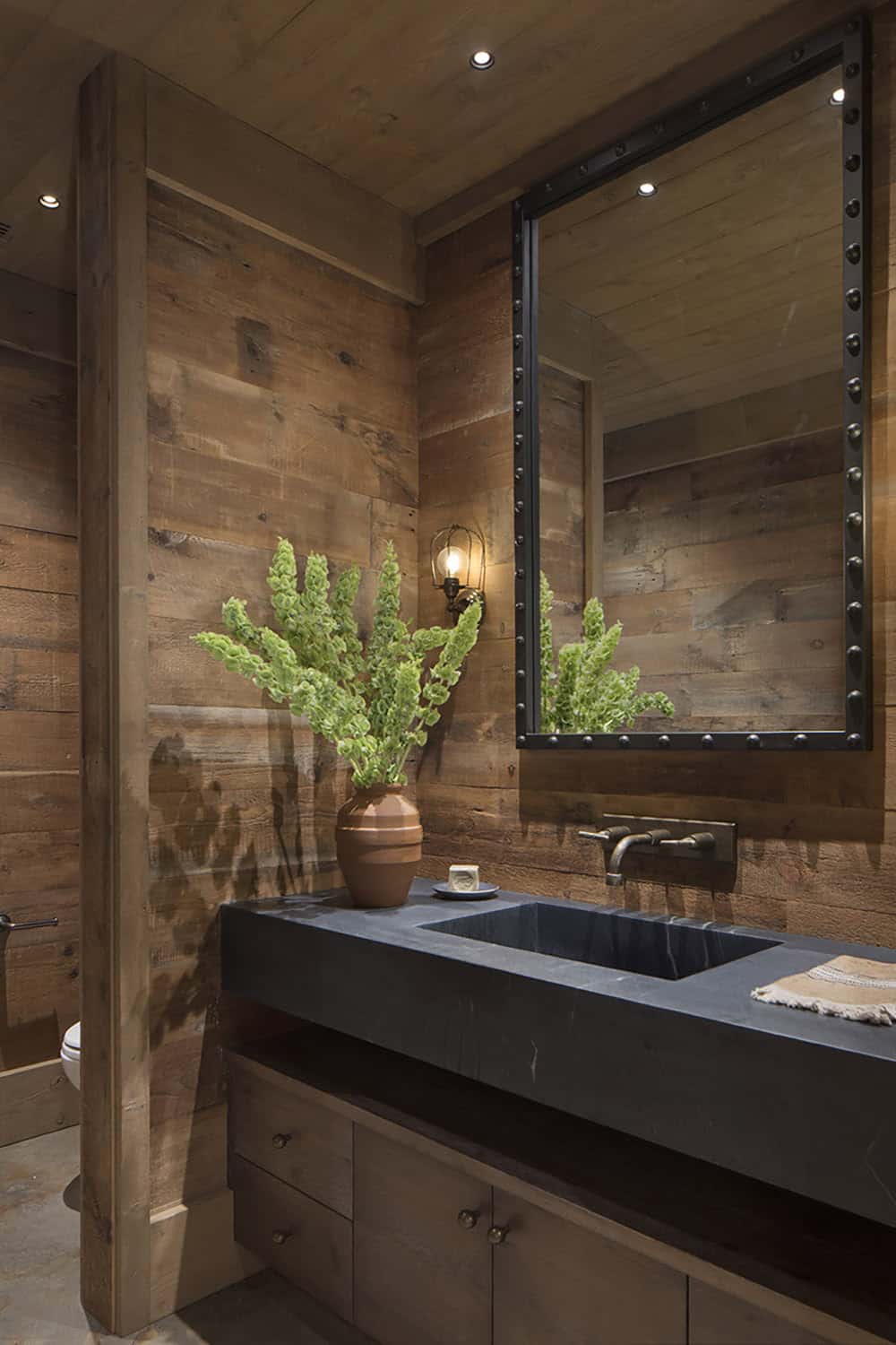 Moody powder room with soapstone sink, riveted mirror and reclaimed wood walls